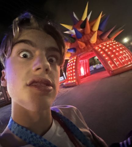 睁大眼睛的自拍，背后是发光的红色充气拱门